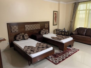 A room with two beds, a sofa, a coffee table, and a patterned rug.
