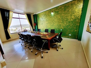 A conference room with a large table, chairs, and a green patterned wall.