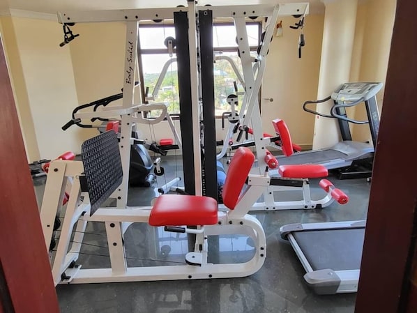 A gym with exercise equipment including a squat rack, benches, and a treadmill.