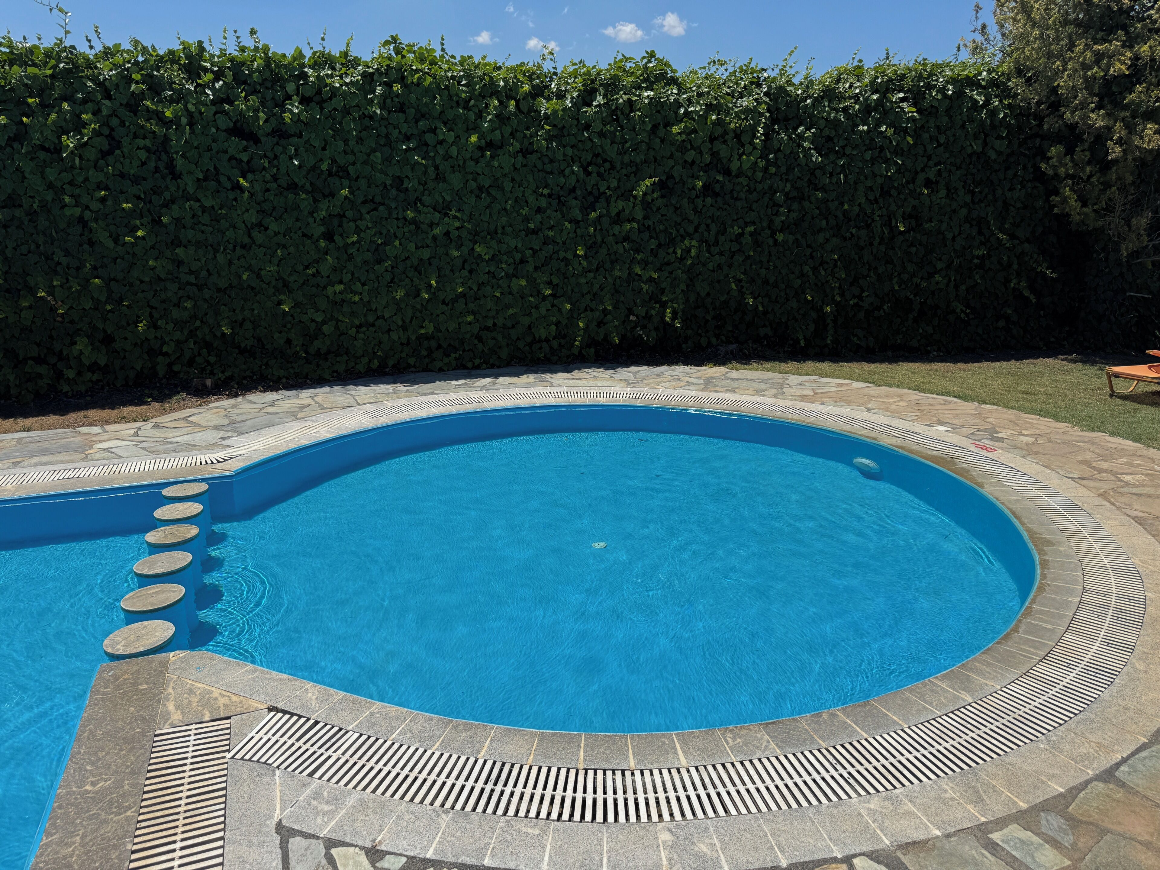 Una piscina con bordi in pietra e gradini che conducono all'acqua.