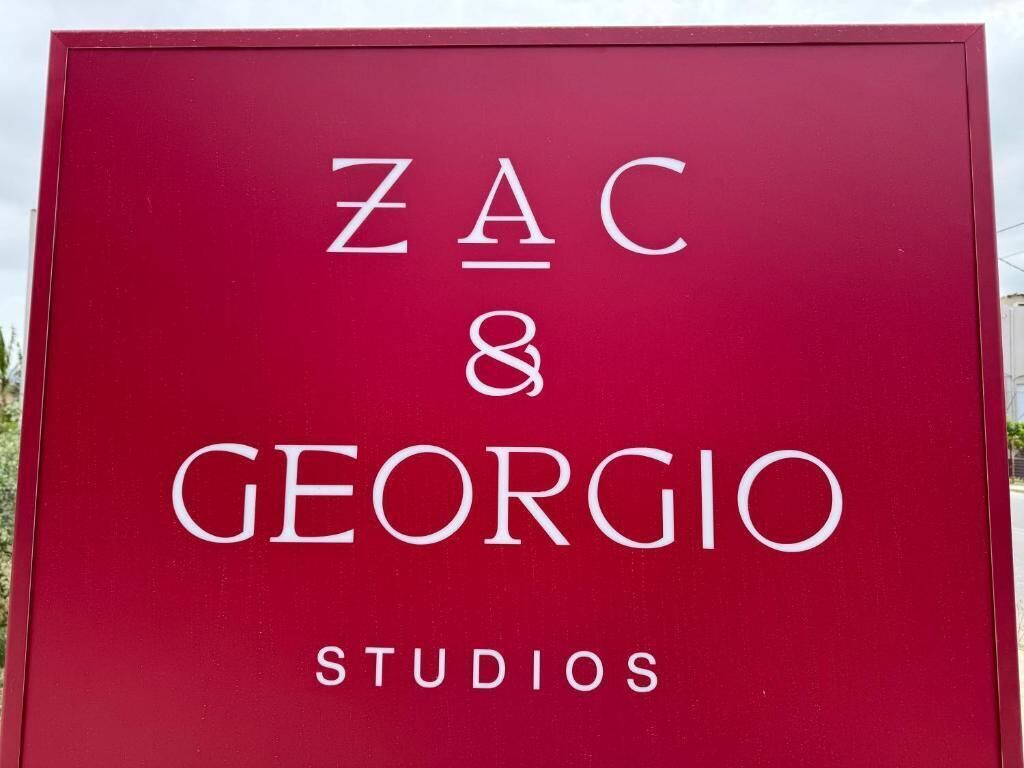 Un cartello color borgogna con la scritta 'ZAC & GEORIO STUDIO' in bianco.