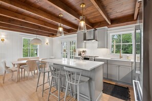 A modern kitchen with a large island, bar stools, and pendant lighting. - Walk to Beach|Sleeps 10| Fire Pit|Hot Tub| Games (Kennebunk)