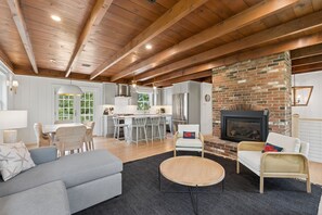 A spacious living area with a fireplace, a dining area, and a kitchen. - Walk to Beach|Sleeps 10| Fire Pit|Hot Tub| Games (Kennebunk)