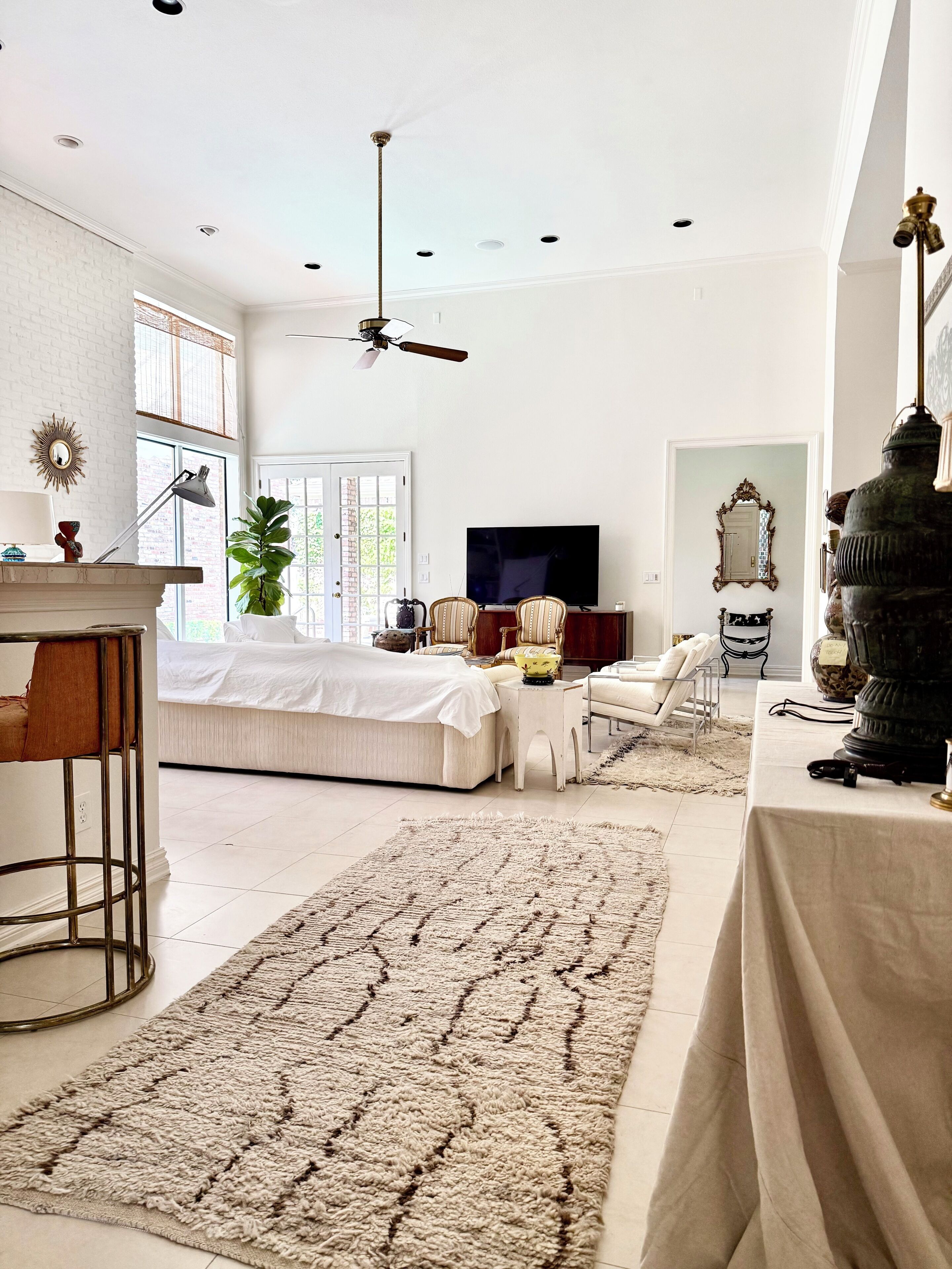 A spacious living room with a large bed, a television, and a ceiling fan.