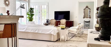 A spacious living room with a large bed, a television, and a ceiling fan.
