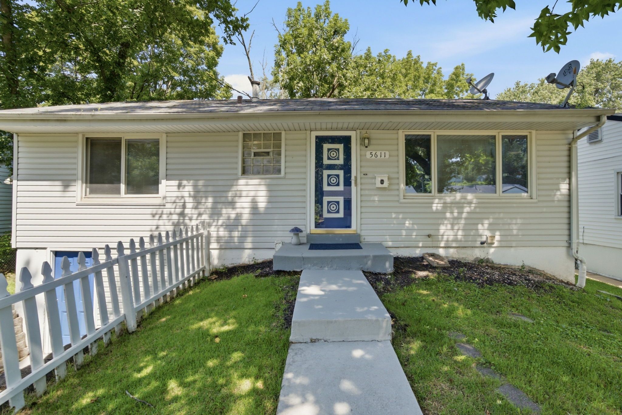 A single-story house with a front porch, a mailbox, and a satellite dish.