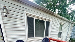 A house with a red deck, two Adirondack chairs, and a white exterior.