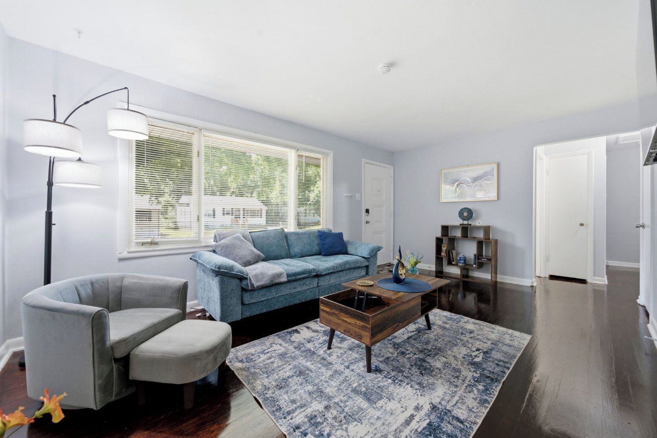 A living room with a blue sofa, a grey armchair, a coffee table, and a floor lamp.