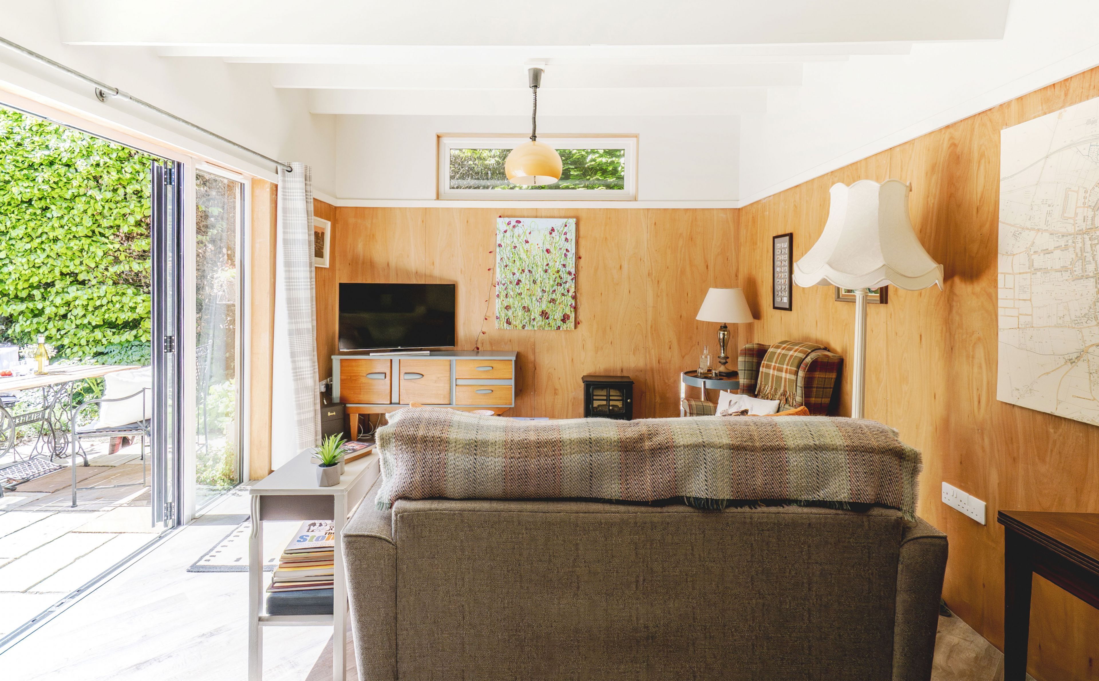 A living room with a sofa, TV, wooden walls, and a map on the wall.