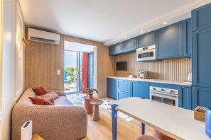A modern kitchen with blue cabinets, a white countertop, and a dining area with a table and chairs. - Waimea - À 200 m de la plage (Capbreton)
