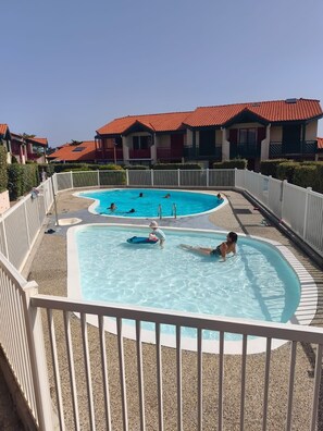 A swimming pool with multiple lanes, surrounded by a white fence, and adjacent to a building with red-tiled roofs. - Waimea - À 200 m de la plage (Capbreton)
