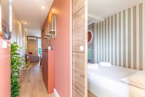A modern hotel room with a wooden floor, a bed with white linens, a large mirror, and a potted plant. - Waimea - À 200 m de la plage (Capbreton)