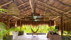 A thatched-roof structure with a hammock, a table with a patterned tablecloth, and potted plants. - Tulum Style Escape | Private Pool & Nature Vibes (Tulum)