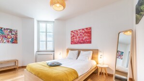 A modern bedroom with a wooden bed, a bedside table, a mirror, and artwork on the walls. - Daisy – Élégant cocon au cœur de Biarritz (Biarritz)