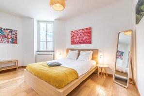 Ein modernes Schlafzimmer mit einem Holzbett, einem Nachttisch, einem Spiegel und Bildern an den Wänden.
