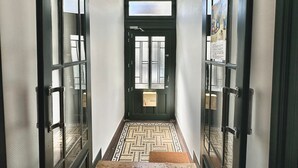 A hallway with a black door, a patterned floor, and glass doors on either side. - Daisy – Élégant cocon au cœur de Biarritz (Biarritz)