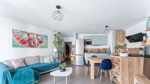 A modern living room with a sofa, coffee table, and a dining area with chairs. - Carnet de route - Appt climatisé avec balcon (Lyon)
