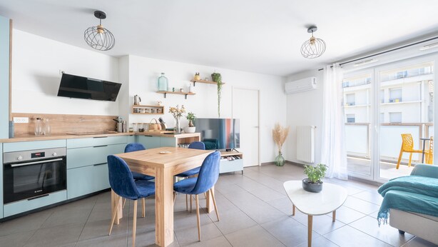 A modern kitchen with a dining area, a flat-screen TV, and a large window. - Carnet de route - Appt climatisé avec balcon (Lyon)