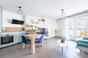 Eine moderne Küche mit Essbereich, einem Flachbildfernseher und einem großen Fenster.