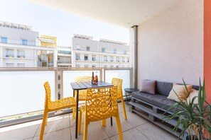 Ein Balkon mit gelben Stühlen, einem Tisch und einer Couch.