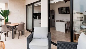 Un espace de vie moderne comprenant une table à manger, des chaises, un canapé et, au fond, une cuisine.