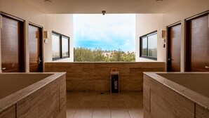 Une salle de bain moderne avec deux lavabos, une fenêtre donnant sur un beau paysage et un extincteur.