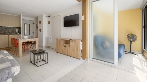 Ein moderner Wohnraum mit Küche, Essbereich und einer großen Schiebeglastür, die auf einen Balkon führt.