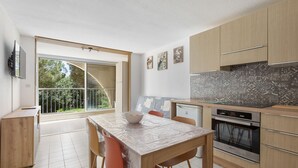 Eine moderne Küche mit Essbereich, großen Fenstern und Blick auf Grünflächen.