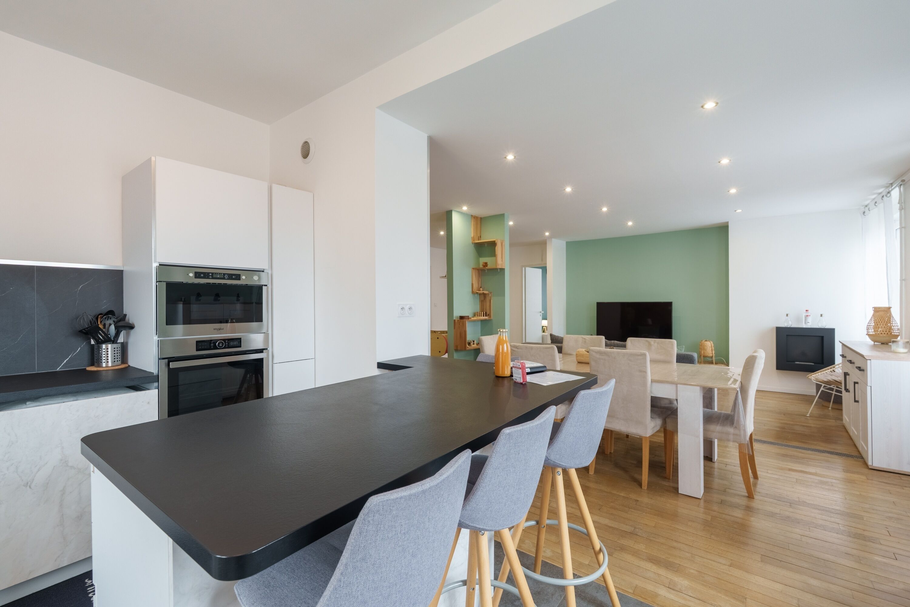 A modern kitchen with a central island, built-in oven, and bar stools.