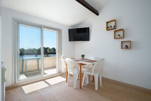 Ein Zimmer mit einer Schiebeglastür, die auf einen Balkon führt, einem an der Wand befestigten Flachbildfernseher und drei kleinen gerahmten Bildern.