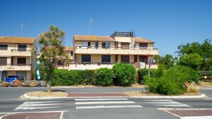 Un edificio residencial con techo plano, varios balcones y un paso de cebra en la calle.