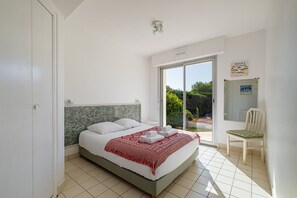 Ein Schlafzimmer mit Bett, Stuhl, Fenster und Tür.