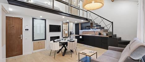 Un interior moderno con comedor, cocina y escalera.