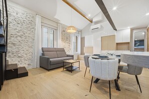 Ein modernes Wohnzimmer mit einer Couch, einem Esstisch, Stühlen, einer Treppe und einer Küchenzeile.