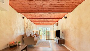 A living room with a sofa, TV, wooden floor, and a red ceiling. - Le Resticas - Triplex climatisé (Rustiques)
