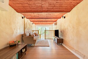 A living room with a sofa, TV, wooden floor, and a red ceiling. - Le Resticas - Triplex climatisé (Rustiques)
