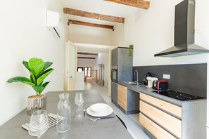 A modern kitchen with a built-in stove, a sink, and a wooden cabinet. - Le Resticas - Triplex climatisé (Rustiques)