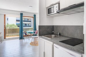 Eine moderne Küche mit eingebauter Mikrowelle, einer Spüle aus Edelstahl und einer schwarzen Induktionskochplatte.