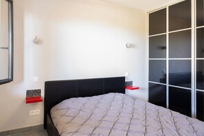 Ein Schlafzimmer mit einem Bett, einem Kleiderschrank, einem roten Regal und einer Fliesenwand.