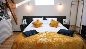 A bedroom with a bed, two nightstands, a radiator, a window with natural light, and a wooden ladder. - Les Clés de Censibele - Charmant gîte pour 12 (Braye)