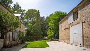 A courtyard with a paved walkway, stone buildings, and a grassy area. - Les Clés de Censibele - Charmant gîte pour 12 (Braye)
