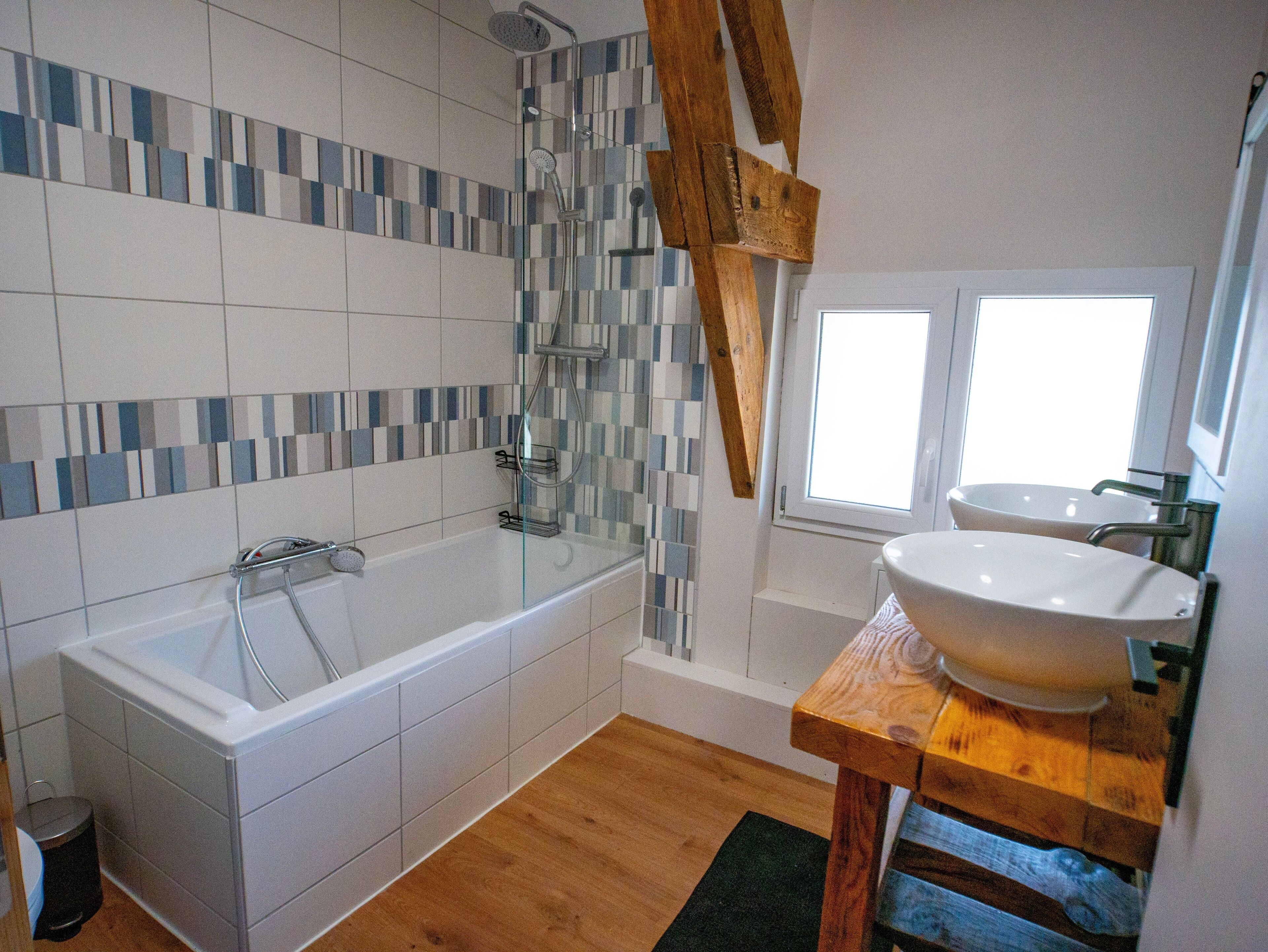 A bathroom with a bathtub, a wooden vanity with a large sink, and a shower.