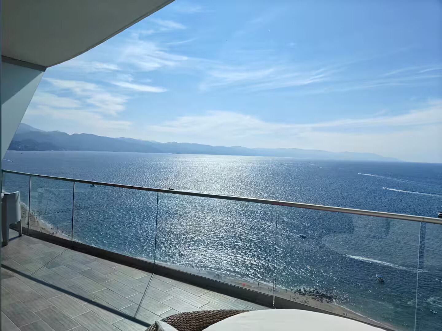 Uma varanda com vista para o mar e montanhas ao longe.
