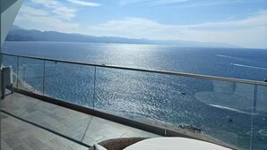 Een balkon met uitzicht op zee en op de verre bergen.