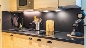 Une cuisine moderne avec des meubles en bois, un four à micro-ondes, une machine à café et un bloc à couteaux.