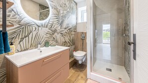 A bathroom with a shower, toilet, vanity, and a mirror. - Le Cocon des sables – climatisé à 100m de la plage (Asnelles)
