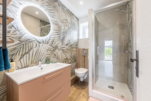 Ein Badezimmer mit Dusche, Toilette, Waschtisch und Spiegel.