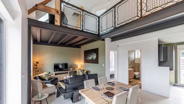 A spacious living area with a dining table, sofas, and a TV. - Le Cocon des sables – climatisé à 100m de la plage (Asnelles)