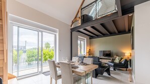 A modern interior with a dining area, a living space, and a staircase. - Le Cocon des sables – climatisé à 100m de la plage (Asnelles)