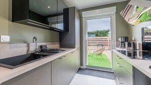 A modern kitchen with a large window, a built-in oven, and a sink. - Le Cocon des sables – climatisé à 100m de la plage (Asnelles)